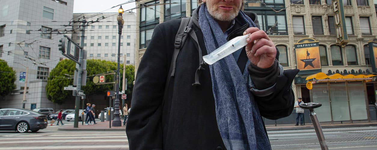 Drug user on the street in California holding Naloxone