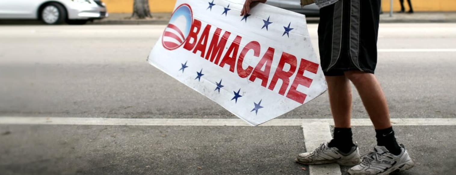 Person carrying an ObamaCare sign on a street