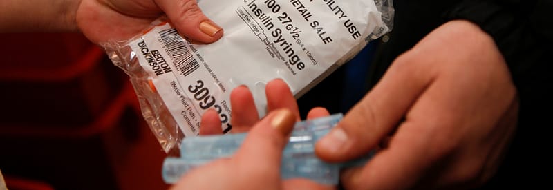 clean syringes being handed from one person to another