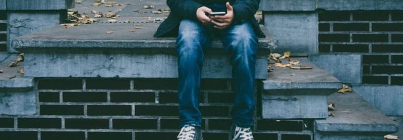 young person sitting alone outside a residence