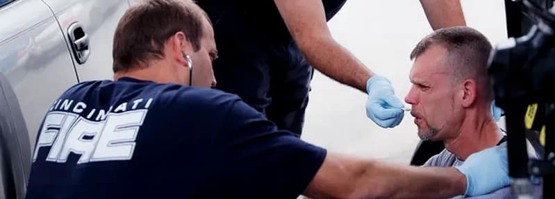 man being administered naloxone by paramedics