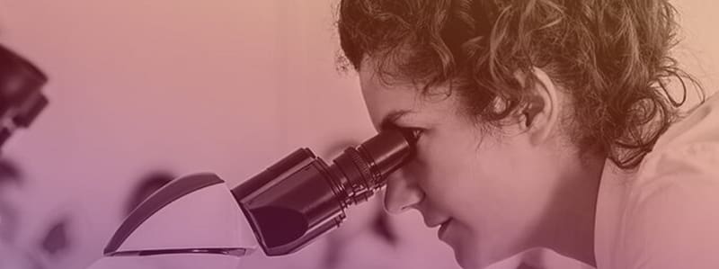 A medical researcher looks into a microscope