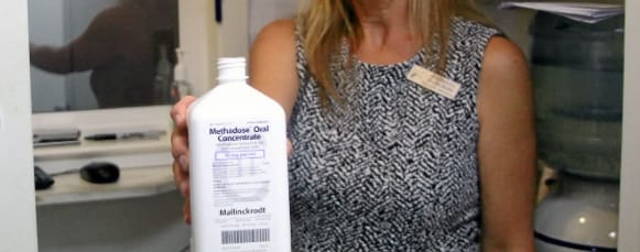Methadone in bottle held by methadone clinic employee