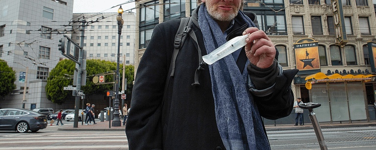 Drug user on the street in California holding Naloxone