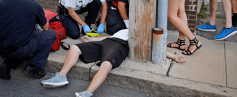 Opioid overdose victim on a sidewalk with paramedics
